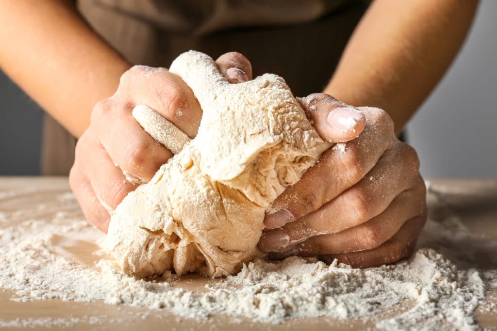 woman kneading flour in kitchen, closeup